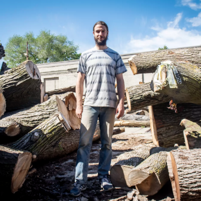 Man standing amongst large logs
